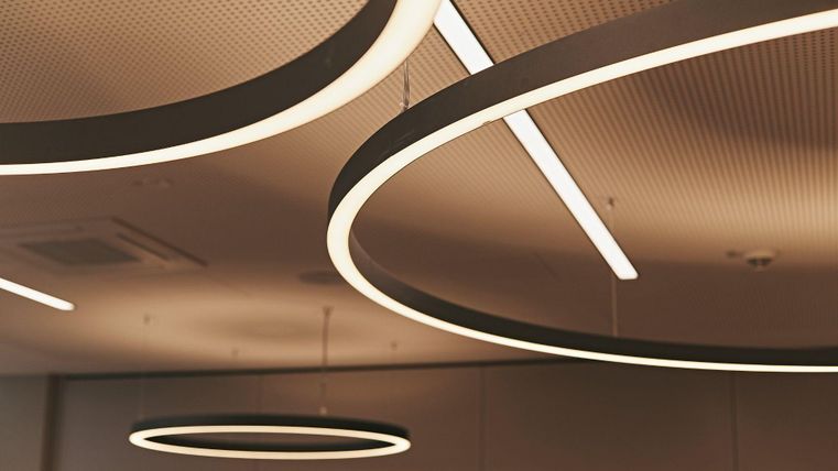 Moderne Deckenbeleuchtung mit kreisförmigen Leuchten in einem Innenraum. Die Leuchten schaffen eine gemütliche und elegante Atmosphäre.