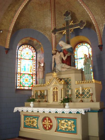 Ein kunstvoller Altar in einer Kapelle mit einer Statue von Maria und Jesus. Bunte Glasfenster verleihen dem Raum einen besonderen Glanz.