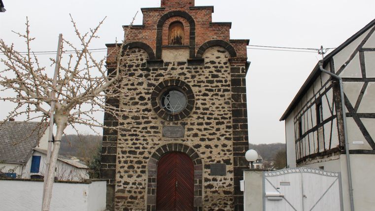 Eine alte Kirche mit einer markanten Fassade aus Stein und Ziegel. Sie steht in einer ruhigen Umgebung zwischen anderen Gebäuden.