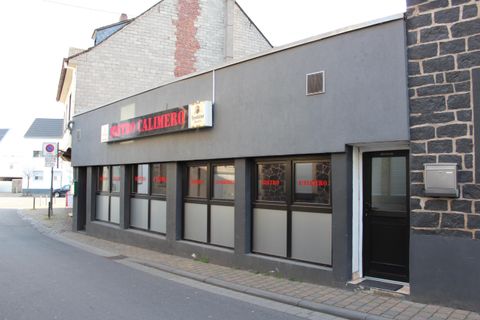 A modern building with large windows and a gray facade paint. It is located on a quiet street.