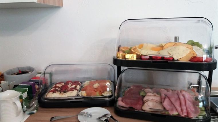 Ein Frühstücksbuffet mit verschiedenen Speisen. Es sind Aufschnitt, Obst und Gebäck in zwei Verkaufsständen untergebracht.