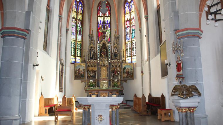 A beautiful church with colorful stained glass windows and a decorative altar. The interior feels bright and inviting.