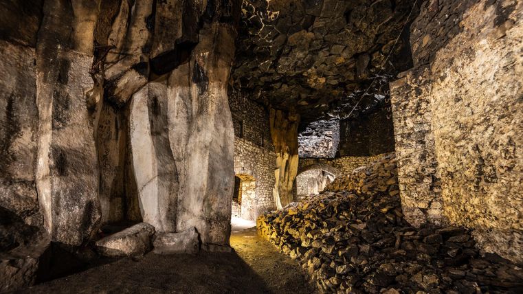 An impressive cave landscape with stone walls and rough rock formations. Soft light illuminates the path and creates a mysterious atmosphere.