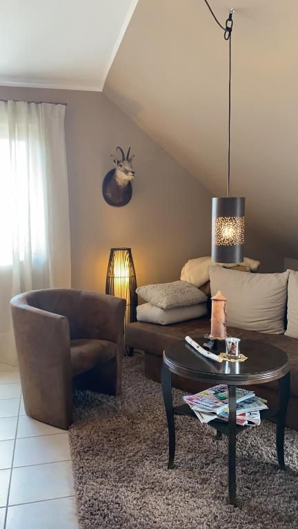 Ein gemütliches Wohnzimmer mit einem beigen Teppich und einem modernen Couchtisch. Der Raum hat eine entspannte Atmosphäre mit einem Sessel und einer stilvollen Lampe.