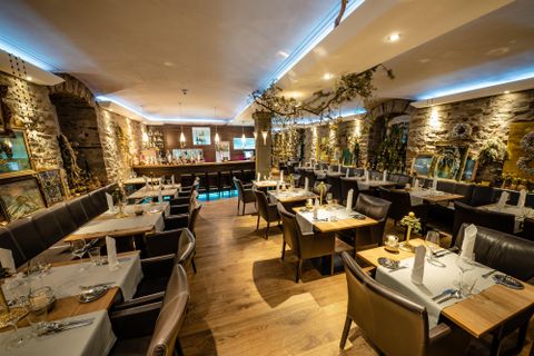 Ein gemütliches Restaurant mit Steindekor und stilvollen Tischen. Die Atmosphäre ist warm und einladend, ideal für ein entspanntes Essen.