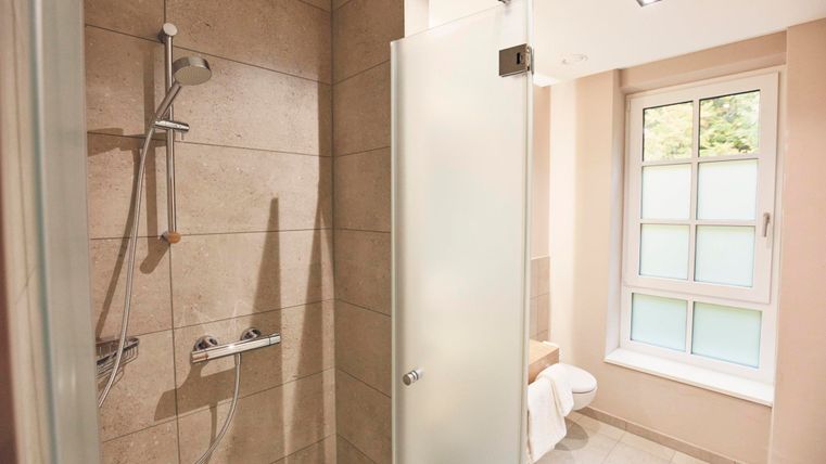 Moderne Dusche in einem hellen Badezimmer mit Fliesen und Fenster. Der Raum wirkt sauber und einladend.