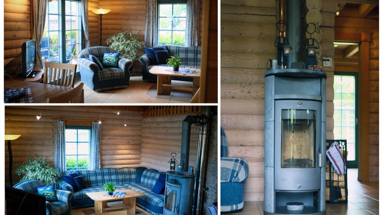 A cozy room with wooden paneling and a blue couch. A table with decorative elements and a stove create an inviting atmosphere.