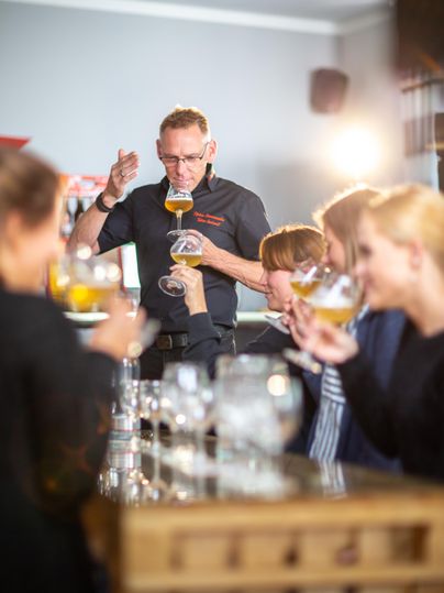 Ein Barkeeper serviert Drinks an eine Gruppe von Gästen in einer gemütlichen Bar. Die Atmosphäre ist freundlich und einladend.