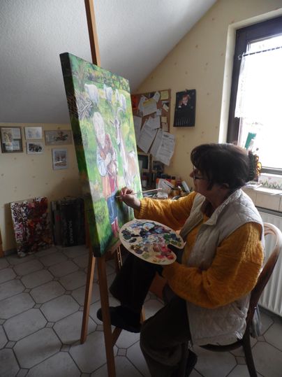 Eine Künstlerin malt konzentriert an einer Leinwand in ihrem Atelier. Farbtöpfe und eine angenehme kreative Atmosphäre sind sichtbar.
