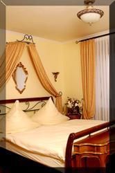 Ein gemütliches Schlafzimmer mit einem großen Bett und eleganten Kissen. Die Wände sind in warmen Farben gehalten, und es gibt dekorative Vorhänge.