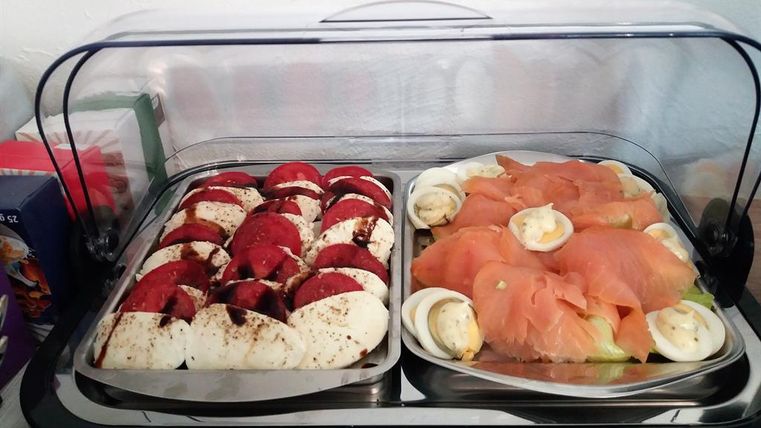 Ein Buffet mit zwei verschiedenen Gerichten. Auf der linken Seite sind Tomaten und Mozzarella, rechts Räucherlachs mit Eiern.