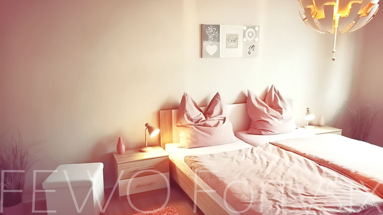 A cozy bedroom with two beds and modern pillows. The soft lighting creates a relaxed atmosphere.
