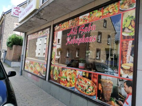 A kebab house with a large display window showcasing a selection of delicious dishes. The signage is clearly visible with the name "Ali Baba Kebaphaus".