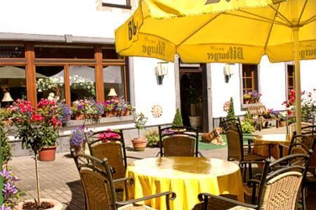 An inviting outdoor café with round tables and yellow umbrellas. Colorful flowers adorn the seating areas and create a cozy atmosphere.