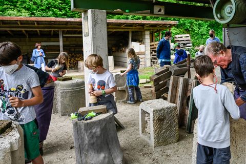 Eine Gruppe von Kindern arbeitet an einem kreativen Projekt im Freien. Sie bearbeiten Materialien und sind konzentriert bei der Sache.