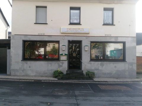 Ein Restaurant mit dem Namen "Punjab" an einer ruhigen Straße. Die Fassade zeigt große Fenster und eine einladende Eingangstür.