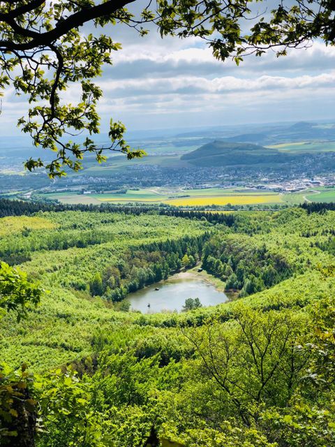Eine hügelige Landschaft mit buntem Laub und sanften Wiesen. Auf dem Hügel steht ein historischer Turm, umgeben von einem bewölkten Himmel.