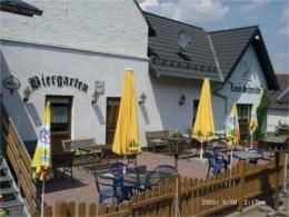 A beer garden with yellow parasols and blue chairs. The building in the background is bright and welcoming.