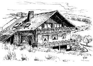 Ein traditionelles Chalet in ländlicher Umgebung. Es hat ein schräges Dach und einen Balkon mit Fensteröffnungen.