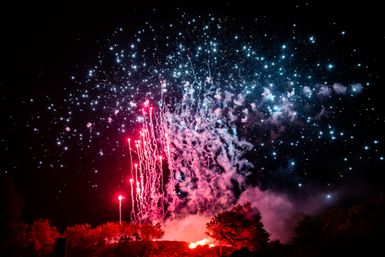 Luftaufnahme eines Höhenfeuerwerks. Die Funken des Feuerwerks sind rot. Die Umgebung leuchtet rot.