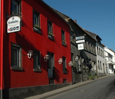 Eine farbenfrohe Straße mit roten und schwarzen Häusern. Es gibt auch Schilder, die auf Unternehmen hinweisen.