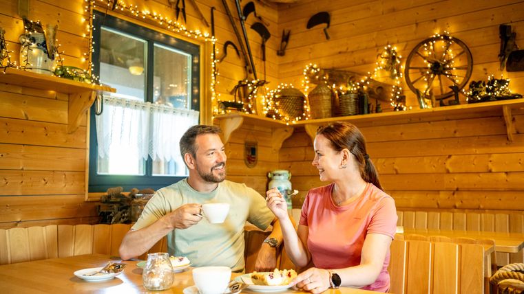 A cozy café with rustic wooden decor. A couple enjoys coffee and cake together.