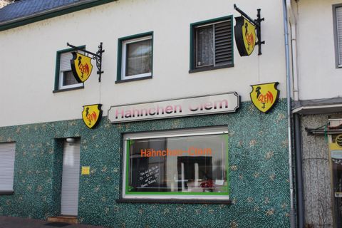 Ein Gebäude mit einer grünen Fassade und einem Schild, das den Namen "Flammkuchen Stern" zeigt. Zwei Wappen befinden sich an der Fassade, die das Bild zieren.