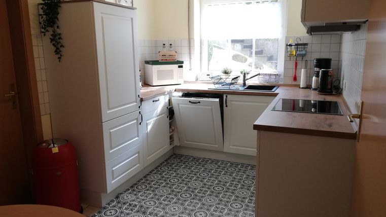 A bright kitchen with modern furniture and a window that lets in daylight. The floor features a decorative pattern.