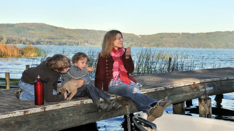 A pier by the water with a woman and two children. They enjoy the view and relax in nature.