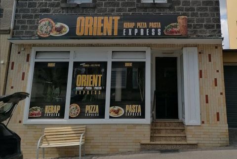 A restaurant named "Orient". It offers kebab, pizza, and pasta and has large windows with advertising posters.