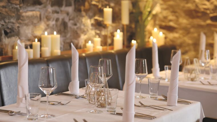 Ein elegantes Restaurant mit schön gedeckten Tischen und Kerzenlicht. Die Atmosphäre ist warm und einladend.