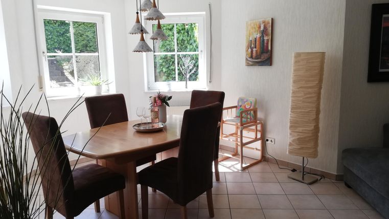 A cozy dining area with a round table and four chairs. Bright walls and plenty of natural light create an inviting atmosphere.
