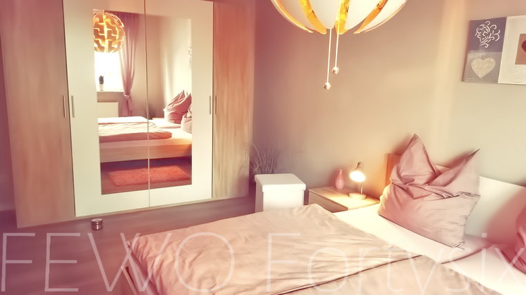 A cozy bedroom with a large bed and a modern wardrobe. A stylish lamp and decorative pictures complement the space.