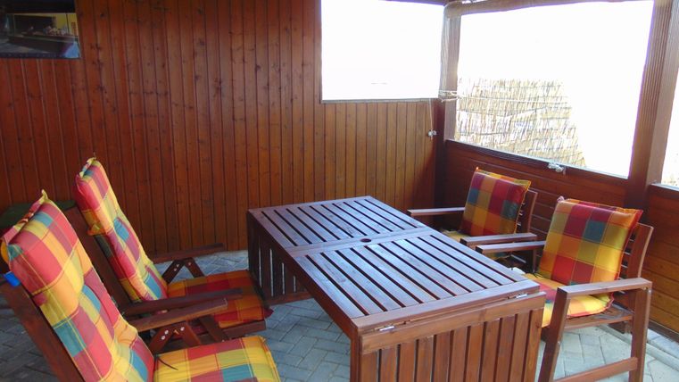 A cozy seating area with a table and colorful chairs in a wooden room. The room has a warm atmosphere with wood paneling.
