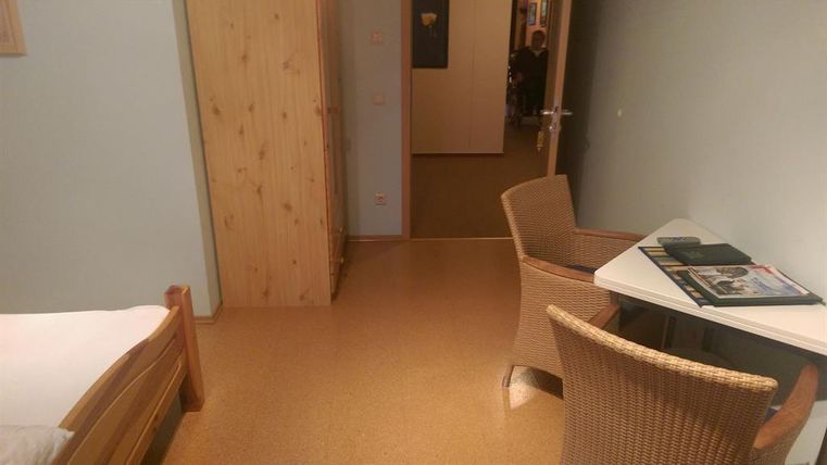 A simple room with a bed, a table, and a chair.
The walls are painted in gentle colors, and the floor is made of light material.