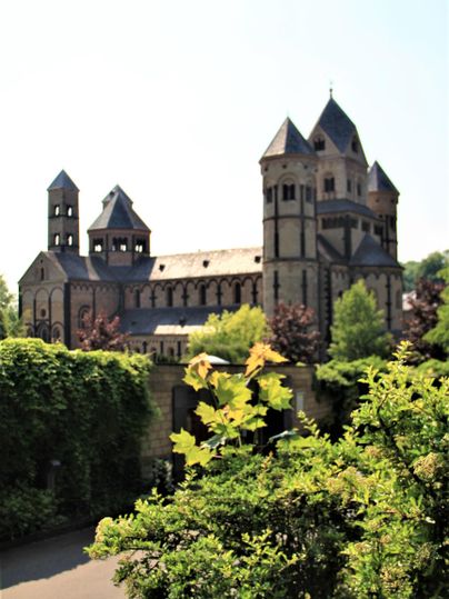 Eine beeindruckende alte Kirche mit Türmen und einem großen Dach. Das Gebäude ist von grünen Pflanzen umgeben und strahlt historische Schönheit aus.