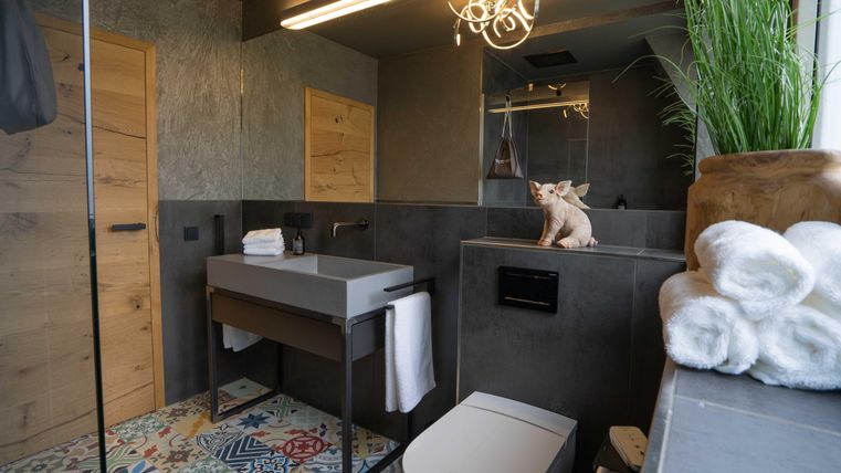 Ein modernes Badezimmer mit einem stilvollen Waschtisch und farbenfrohen Fliesen. Eine dekorative Pflanze und Handtücher vervollständigen die angenehme Atmosphäre.