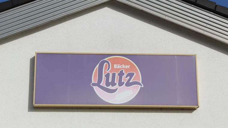 Ein Schild mit dem Namen „Bäcker Lutz“ in freundlichen Farben. Es befindet sich an der Wand eines Gebäudes.