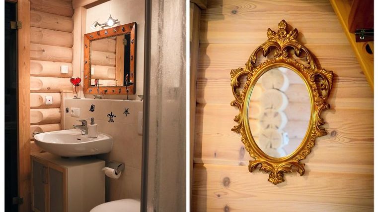 A small bathroom with wooden walls, a sink, and a mirror. On the right side is an elegant, golden frame around a round mirror.