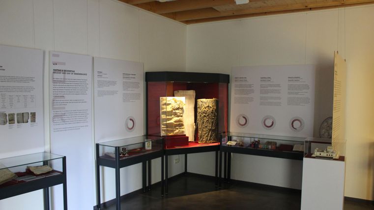 Ein Ausstellungsraum mit Vitrinen und Informationswänden. Die Exponate sind gut beleuchtet und zeigen historische Objekte.