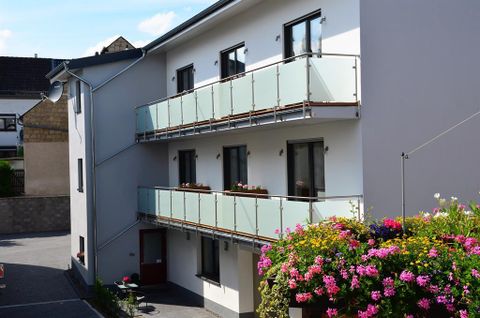 Ein modernes Gebäude mit Balkonen und bunten Blumen. Es befindet sich in einer ruhigen Umgebung.
