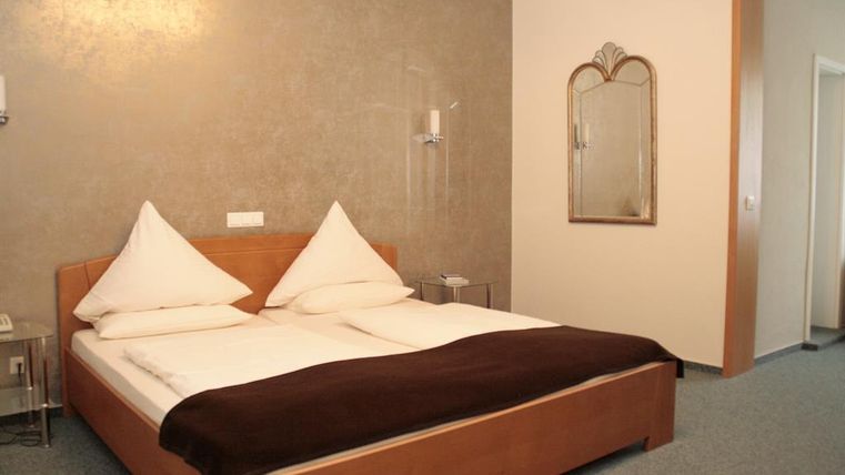 A cozy bedroom with a double bed and elegant pillows. The room has a relaxed atmosphere and a modern mirror on the wall.
