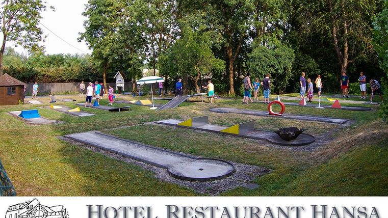 Eine Minigolfanlage mit 18 Bahnen und bunten Hindernissen. Viele Menschen genießen ihre Zeit im Freien zwischen Bäumen und Grünflächen.