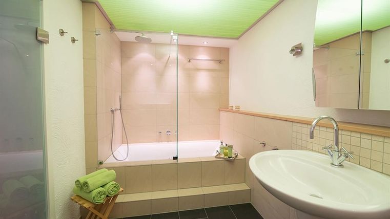 Ein modernes Badezimmer mit einer Dusche und einer Badewanne. Die Wände sind hell gefliest, und frische Handtücher liegen bereit.