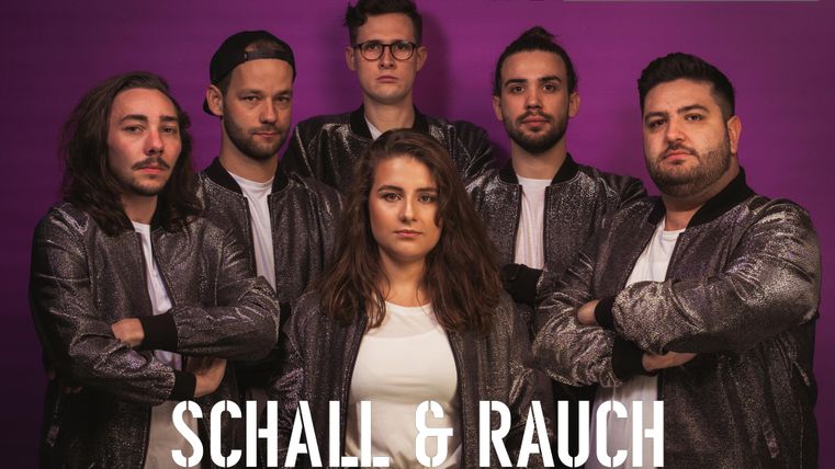 Eine Band namens "Schall & Rauch" mit sechs Mitgliedern in metallischen Jacken steht vor einem lila Hintergrund. Alle schauen in die Kamera und strahlen eine energiegeladene Atmosphäre aus.