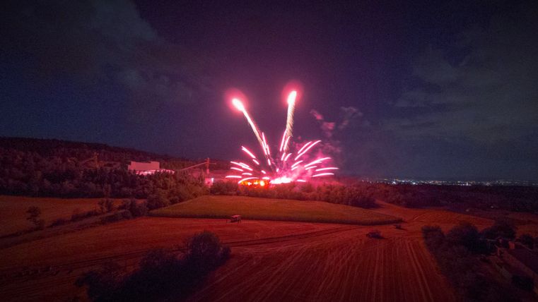 Aufnahme eines Bodenfeuerwerks. Die Funken des Feuerwerks sind rot. Die Umgebung leuchtet rot.
