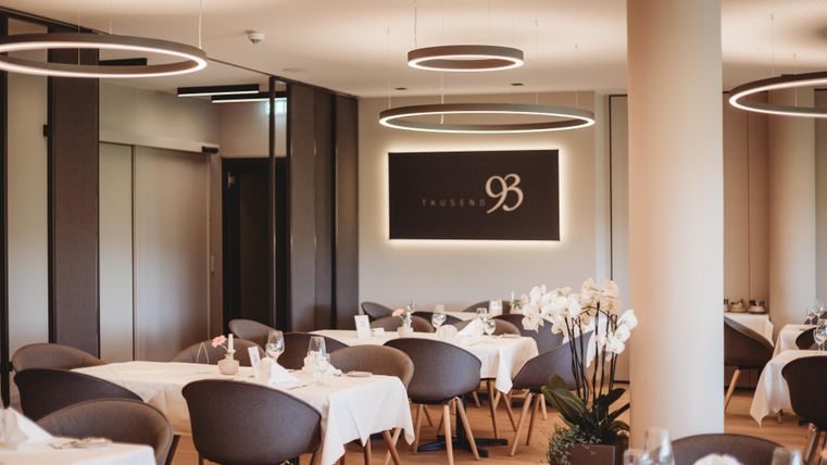 Ein elegantes Restaurant mit stilvollen Tischen und modernen Leuchten. Die Atmosphäre ist hell und einladend, ideal für ein besonderes Dining-Erlebnis.