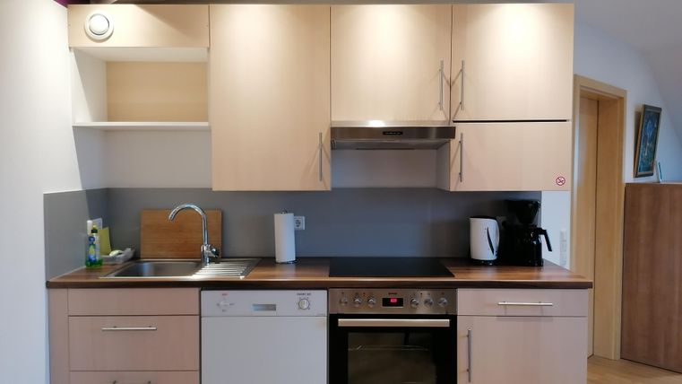 A modern kitchen with wooden cabinets and several appliances. It contains a sink, a dishwasher, and a stove.