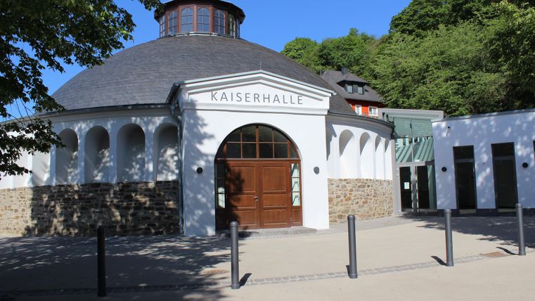 De Kaiserhal is een opvallend gebouw met een rond dak en klassieke architectonische elementen. Omgeven door bomen straalt het een elegante sfeer uit.