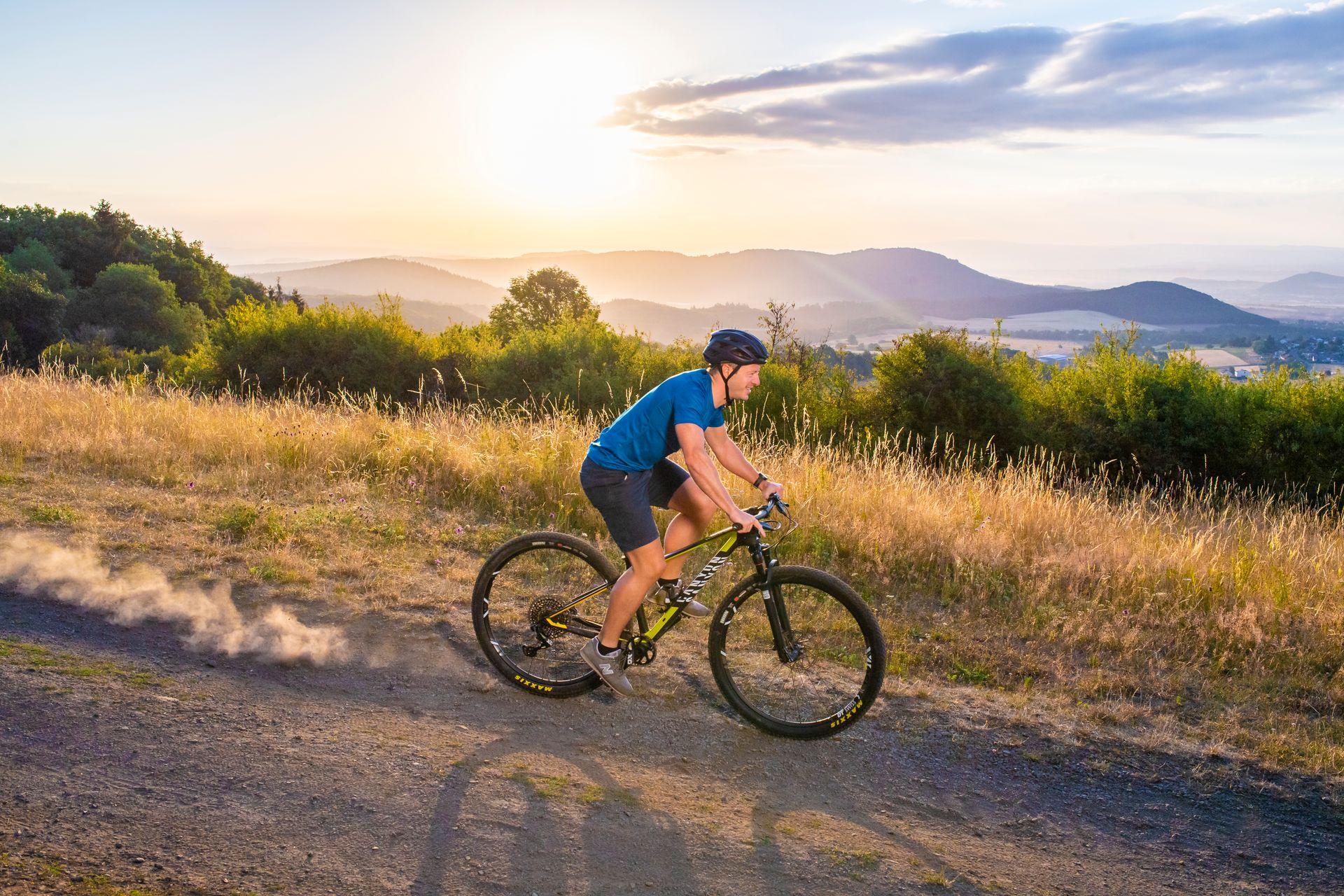 Mountainbikefahrer fährt bei Sonnenuntergang einen Berg hinunter.